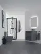 Waschtisch mit schwarz-mattierter Ideal Standard Armatur, Wandmontage und zwei Schubladen. Sichtbarer Handtuchhalter und Dusche im Hintergrund. Grauer Bodenbelag.